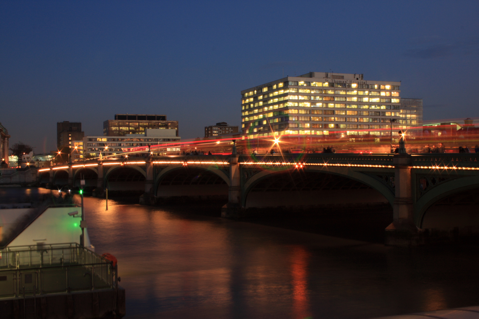 Traffic flowing over Westminster Bridge at dusk.