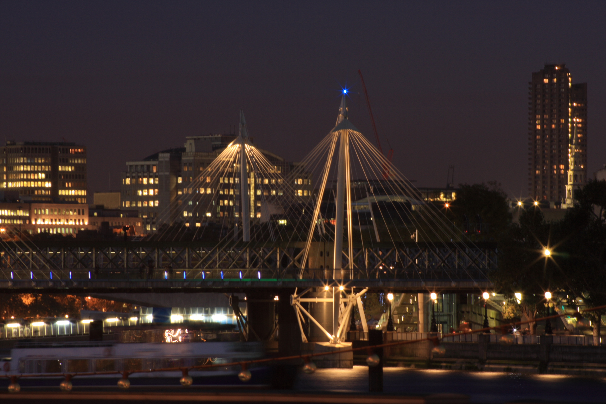 Hungerford Bridge on the Thames illuminated at night.