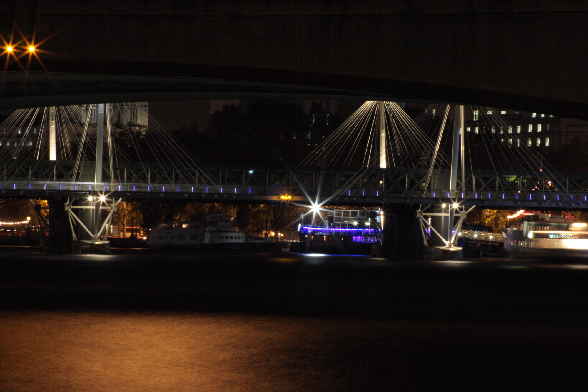 Boats moored on the Thames at night.